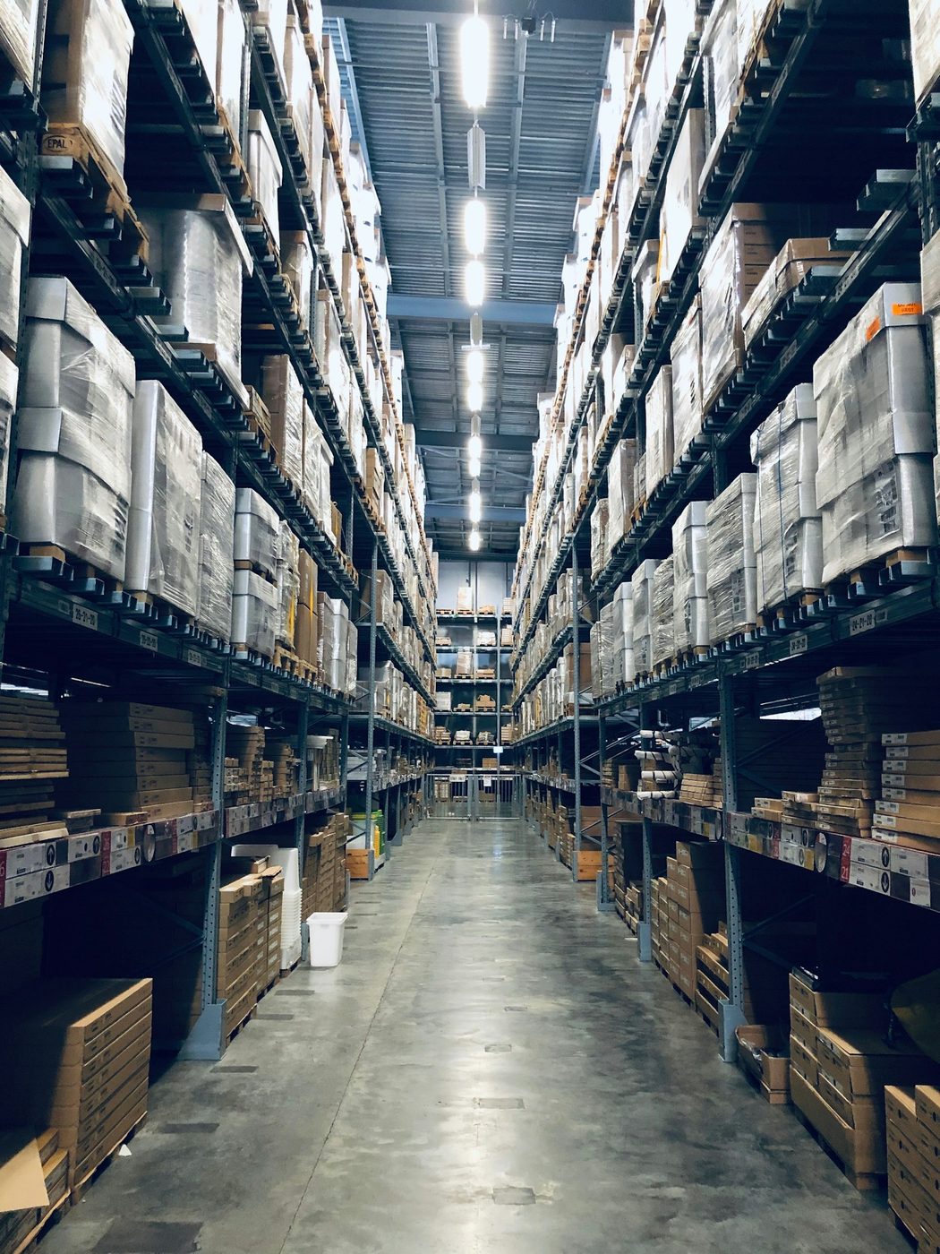 Lorong rak gudang dengan palet barang